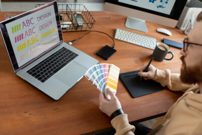 Man in front of laptop with color samples; copyright: Pressmaster
