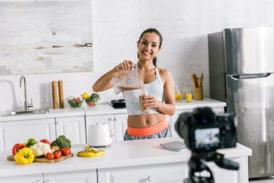 A young woman prepares a smoothie for the camera