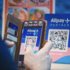 Eine Person nutzt die mobile Bezahl-Funktion von Alipay, indem er einen QR-Code mit seinem Smartphone abfotografiert.