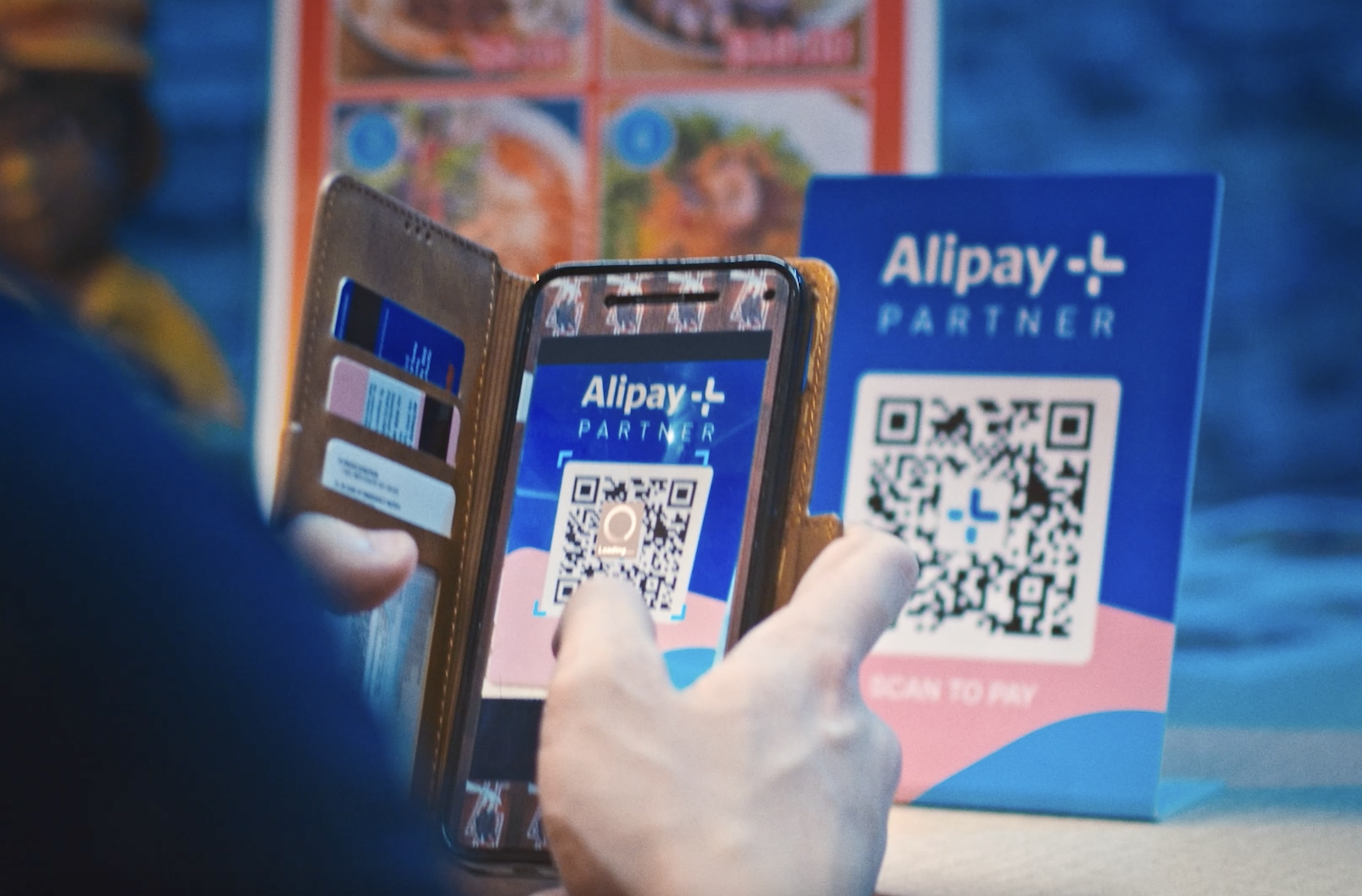 Eine Person nutzt die mobile Bezahl-Funktion von Alipay indem er einen Qr-Code mit seinem Smartphone Abfotografiert.