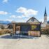 A small grocery store of Billa in a container on a parking lot in front of alpine scenery