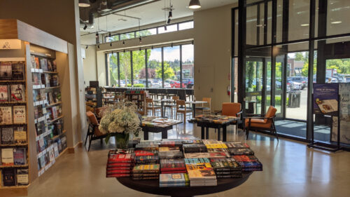 Ein Café mit Sitzplätzen und Fenstern nach draußen, dazwischen Büchertische