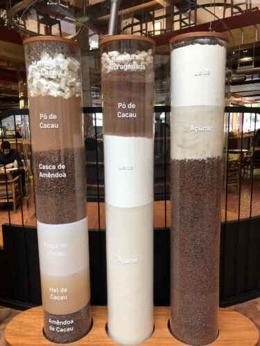 Three glass cylinders labeled and filled with chocolate ingredients