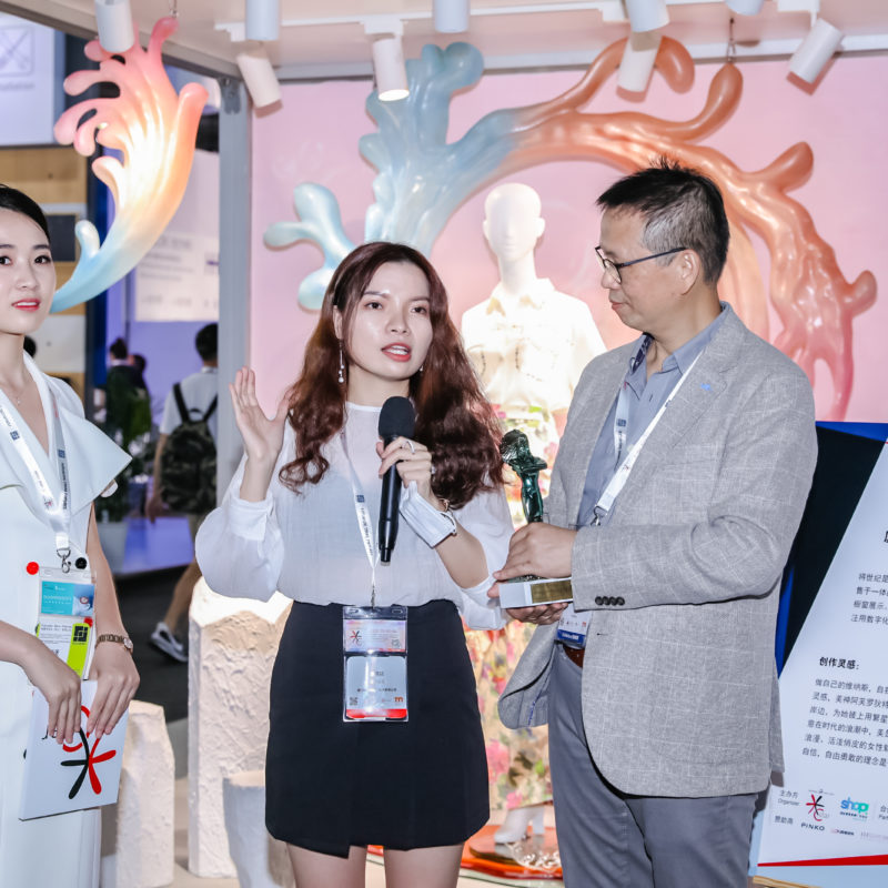 Three people are standing in front of an exhibition stand having a conversation