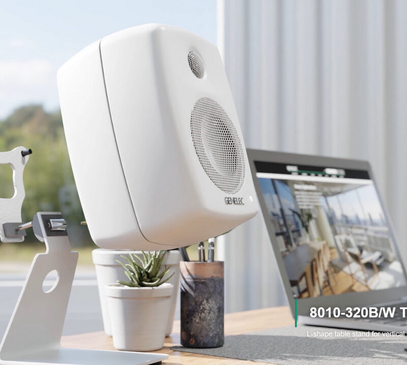 White speaker on a desk next to a laptop