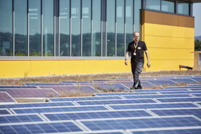 Photovoltaic system on the roof of a Globus. A Globus employee walks between the plants.
