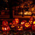 Many pumpkins stand side by side in a meadow with Halloween faces