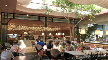 The café Le Parc by tashas with occupied tables and a tree in the room; Copyright: Messe Düsseldorf/Moebius