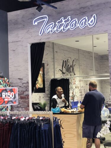 Tattoo Studio in einem Sportscene Geschäft, zwei Menschen unterhalten sich; Copyright: Messe Düsseldorf/Moebius
