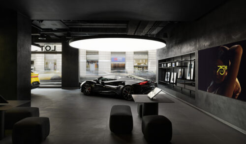The inside of a new Lotus flagship store with a big round light element covering the ceiling, under it a Lotus sports car