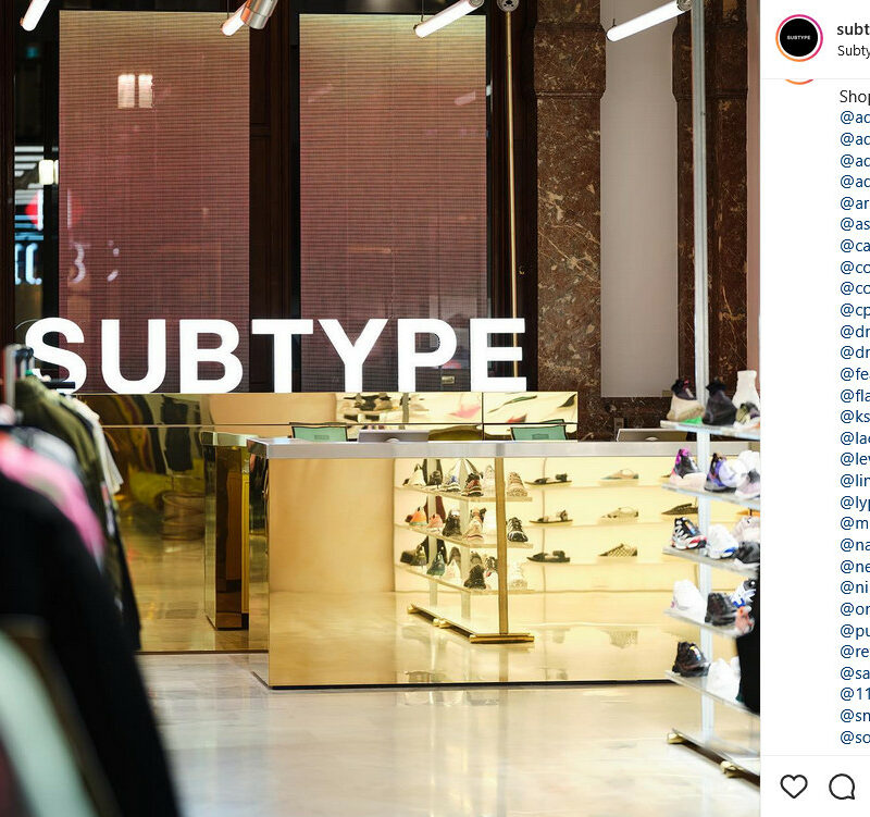 An Instagram post of a clothing store with a gold checkout counter, brand names tagged to the right