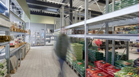 Shelves in a hardware store, a customer walks through an aisle