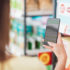 Person holding smartphone in front of a shelf in a store; copyright: panthermedia.net/stokkete