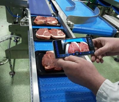 Someone films a conveyor belt with fresh meat with a smartphone