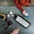 Several products and a tablet on a table and a person holding a smartphone; Copyright: Blake Wisz/Unsplash