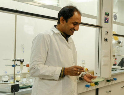 A scientist in a laboratory holding a Petri dish and a pipette