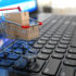 A small shopping cart standing on the keyboard of a laptop