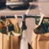 Two paper grocery bags with green food hanging at the handle bars of a bicycle