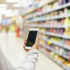 Person holding a smartphone in front of supermarket shelf