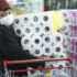 Frau mit Maske, die Toilettenpapier in den Einkaufswagen packt; copyright: Rawpixel