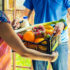 Man handing over grocery delivery in a basket to woman; copyright: PantherMedia/Ronalds Stikans