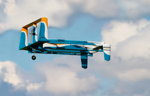 Blau, weiß, orange Prime Air Drohne in der Luft; Copyright: Amazon