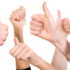 Several hands in the air with their thumbs up