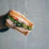 Sandwich welches in der Hand gehalten wird vor einer Betonwand
