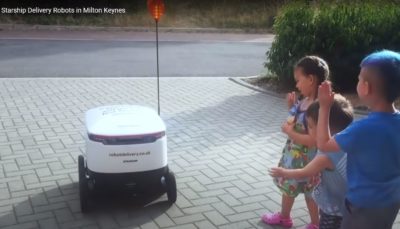 Three children standing next to a white self-driving robot