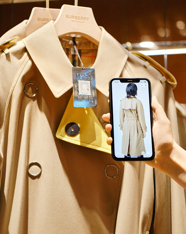 Eine Hand hält ein Smartphone vor ein Kleidungsstück