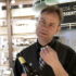 Mann an einer Theke hält eine Weinflasche und gestikuliert beim Sprechen; copyright: beta-web GmbH
